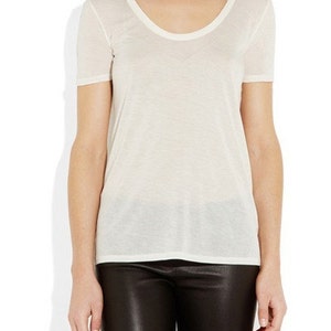 May include: A white scoop neck t-shirt with short sleeves. The t-shirt is made of a soft, lightweight fabric.