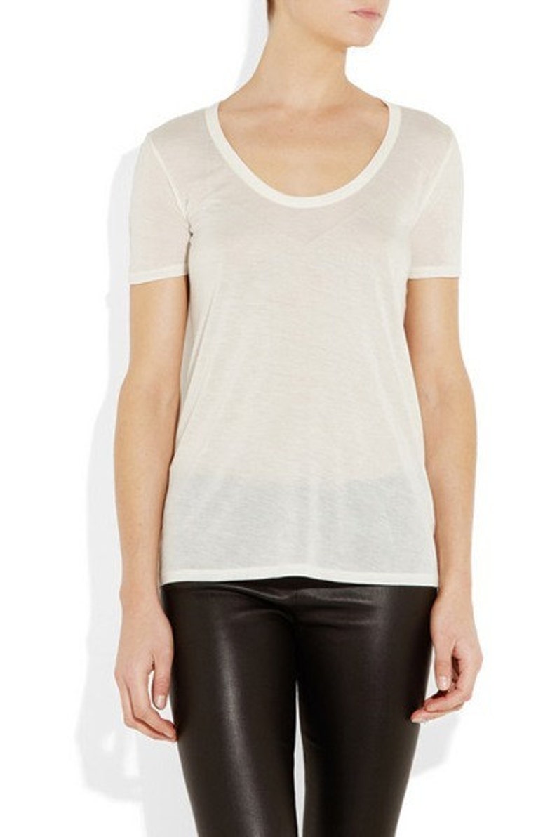 May include: A white scoop neck t-shirt with short sleeves. The t-shirt is made of a soft, lightweight fabric.