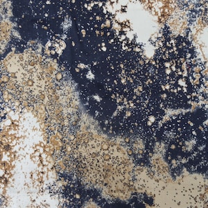 May include: Abstract textile pattern featuring a blend of navy blue, white, and tan hues. The design has a mottled appearance with irregular shapes and speckled details, creating a textured visual effect. The fabric appears to be soft.