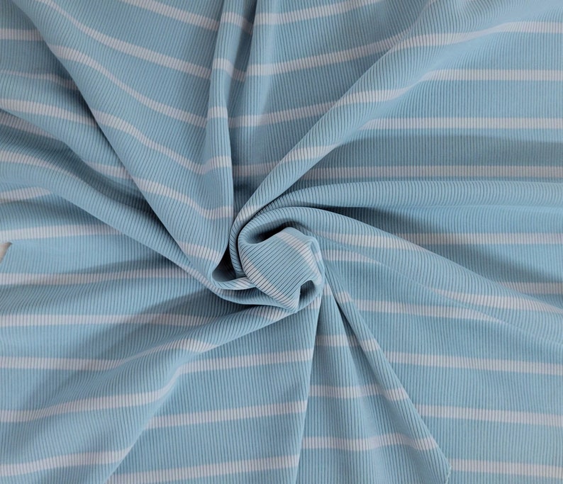 May include: A close-up of a blue and white striped fabric. The fabric is ribbed and has a soft, textured feel.
