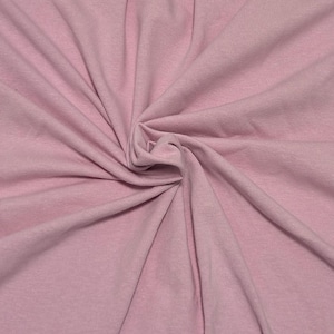 May include: A solid light pink fabric with a soft, matte texture. The material is gathered in the center, creating natural folds and drapes that radiate outward, showcasing the consistent pastel pink color and the fine weave of the textile.