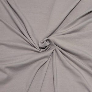 May include: A solid light gray fabric with a smooth, matte texture. The material is gathered in the center, creating soft, radiating folds and drapes that extend outward toward the edges, showcasing the consistent color and fine weave of the textile.