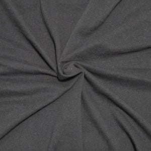 May include: Close-up of a dark gray fabric with a textured surface. The fabric is gathered in a swirl, creating folds and shadows. The material appears to be soft and flexible, suitable for clothing or other textile projects.