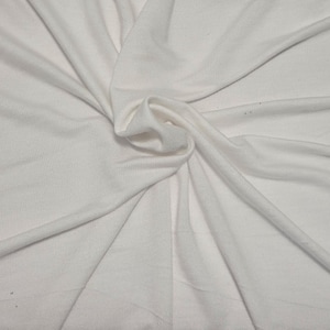May include: A solid white fabric with a smooth, matte texture, arranged in a central swirl pattern that creates radiating folds and soft shadows across the surface, highlighting the consistent color and fine weave of the material throughout.
