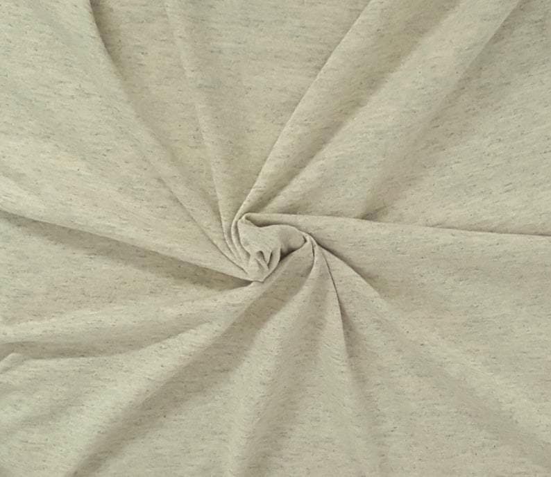Puede incluir: Una tela de color beige claro con una textura jaspeada que presenta peque&ntilde;as motas m&aacute;s oscuras por todo el material. El tejido est&aacute; fruncido en el centro, creando pliegues y drapeados suaves y radiantes que resaltan el patr&oacute;n moteado uniforme.