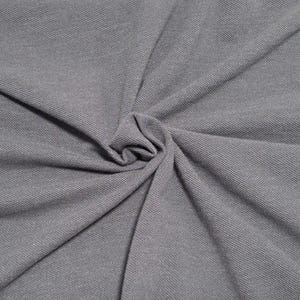 May include: Close-up of gray fabric with a textured surface. The fabric is gathered in the center, creating a swirling pattern. The material appears to be soft and pliable, with visible woven threads. The overall color is a muted gray.