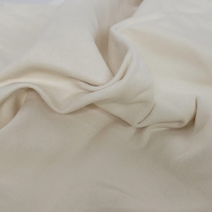 May include: A close-up of a white, soft, and textured fabric. The fabric is folded and draped, showing its smooth and luxurious texture.