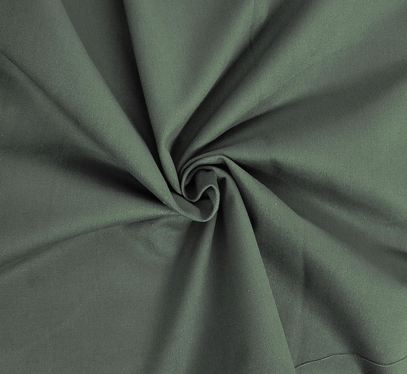 May include: A close-up of a dark green fabric with a smooth texture. The fabric is folded and draped, creating a soft, flowing look.