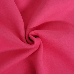 May include: A vibrant hot pink fabric with a soft, matte texture. The material is gathered in the center, creating deep, flowing folds and shadows that highlight the consistent, solid color and the smooth, uniform surface of the textile.