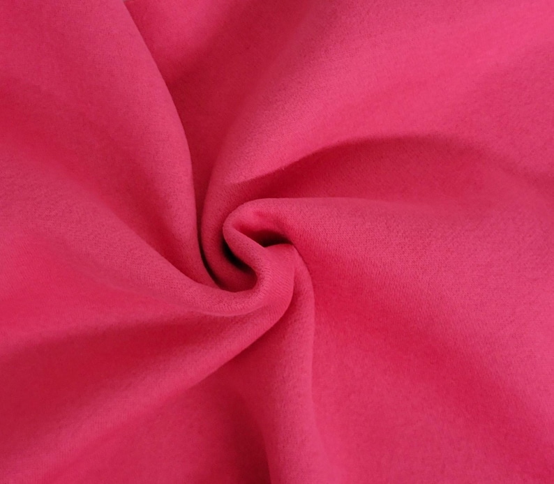 May include: A vibrant hot pink fabric with a soft, matte texture. The material is gathered in the center, creating deep, flowing folds and shadows that highlight the consistent, solid color and the smooth, uniform surface of the textile.