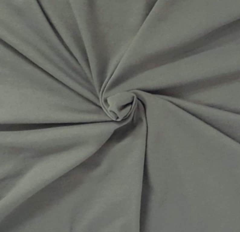 Puede incluir: Una tela de color gris medio s&oacute;lido con una textura suave y mate. El material est&aacute; reunido en el centro, creando una serie de pliegues radiantes y sombras suaves que se extienden hacia los bordes del marco, resaltando la ca&iacute;da.