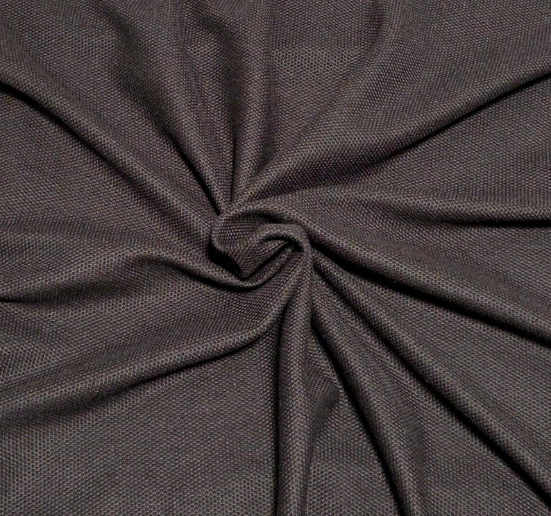 May include: Close-up of a dark brown fabric with a textured, woven appearance. The material is gathered and draped, creating folds and shadows. The fabric has a subtle sheen, and the weave is visible throughout the image.
