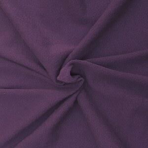 May include: A close-up of a soft, purple fabric with a textured, ribbed surface. The fabric is folded and draped, creating a smooth, flowing texture.