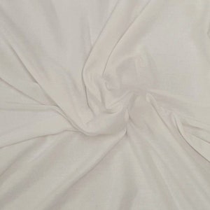 May include: White fabric with a smooth, soft texture. The fabric is draped and folded, creating a flowing, elegant look.