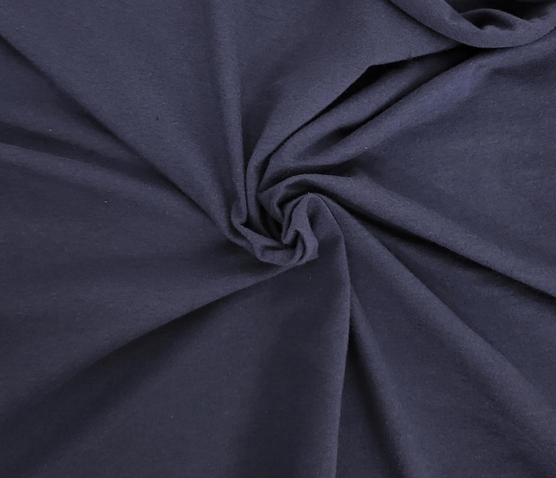 Puede incluir: Una tela de color azul marino oscuro s&oacute;lido con un acabado mate, que presenta una textura suave y pliegues naturales que crean un patr&oacute;n arremolinado y fruncido en la superficie. El material parece opaco y uniforme, con sutiles luces y sombras.