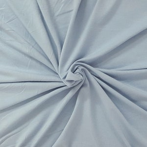 May include: A close-up of a light blue fabric, showing the texture and drape of the material.