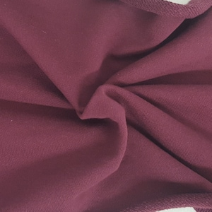 May include: Close-up of a folded piece of burgundy fabric. The fabric has a soft texture and a visible knit pattern. The edges are finished with a darker, ribbed trim. The overall appearance suggests a garment or textile material.