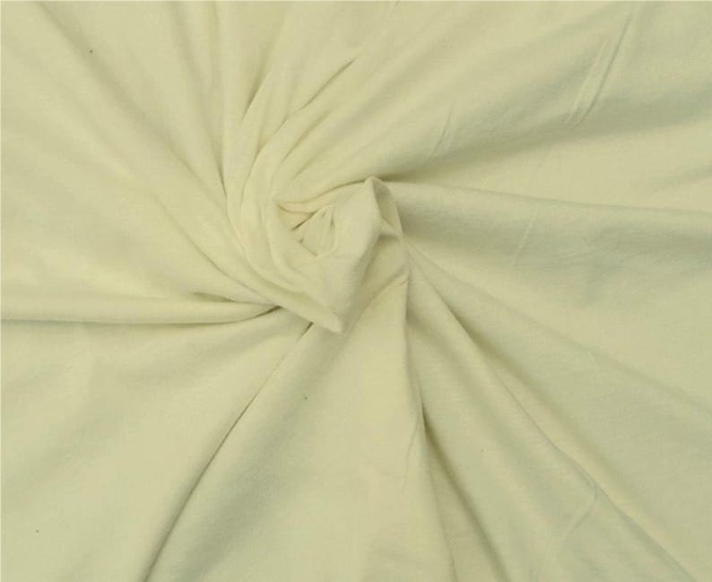 Puede incluir: Una tela de color crema claro s&oacute;lido con una textura suave y mate. El material est&aacute; recogido en el centro, creando pliegues y drapeados naturales que irradian hacia afuera a trav&eacute;s de la superficie, resaltando el color suave y consistente.