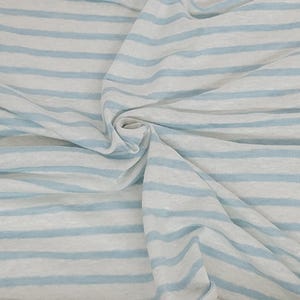 May include: White fabric with light blue stripes. The fabric is folded and wrinkled.