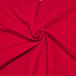 May include: A vibrant red fabric with a soft, matte texture. The material is gathered in the center, creating natural, flowing folds and deep shadows that radiate outward, highlighting the consistent, solid red color across the entire surface.