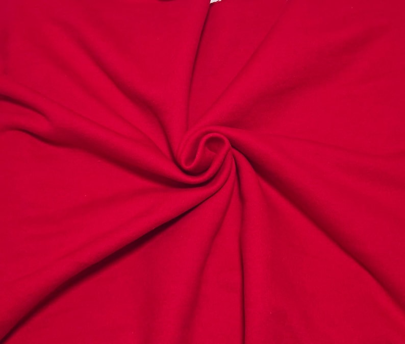 May include: A vibrant red fabric with a soft, matte texture. The material is gathered in the center, creating natural, flowing folds and deep shadows that radiate outward, highlighting the consistent, solid red color across the entire surface.