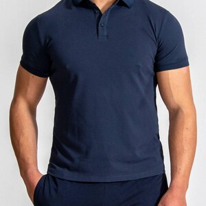 May include: Navy blue polo shirt with short sleeves and a classic collar. The shirt has a three-button placket and is made of a soft, breathable fabric. The shirt is a solid color and is suitable for casual or semi-formal wear.