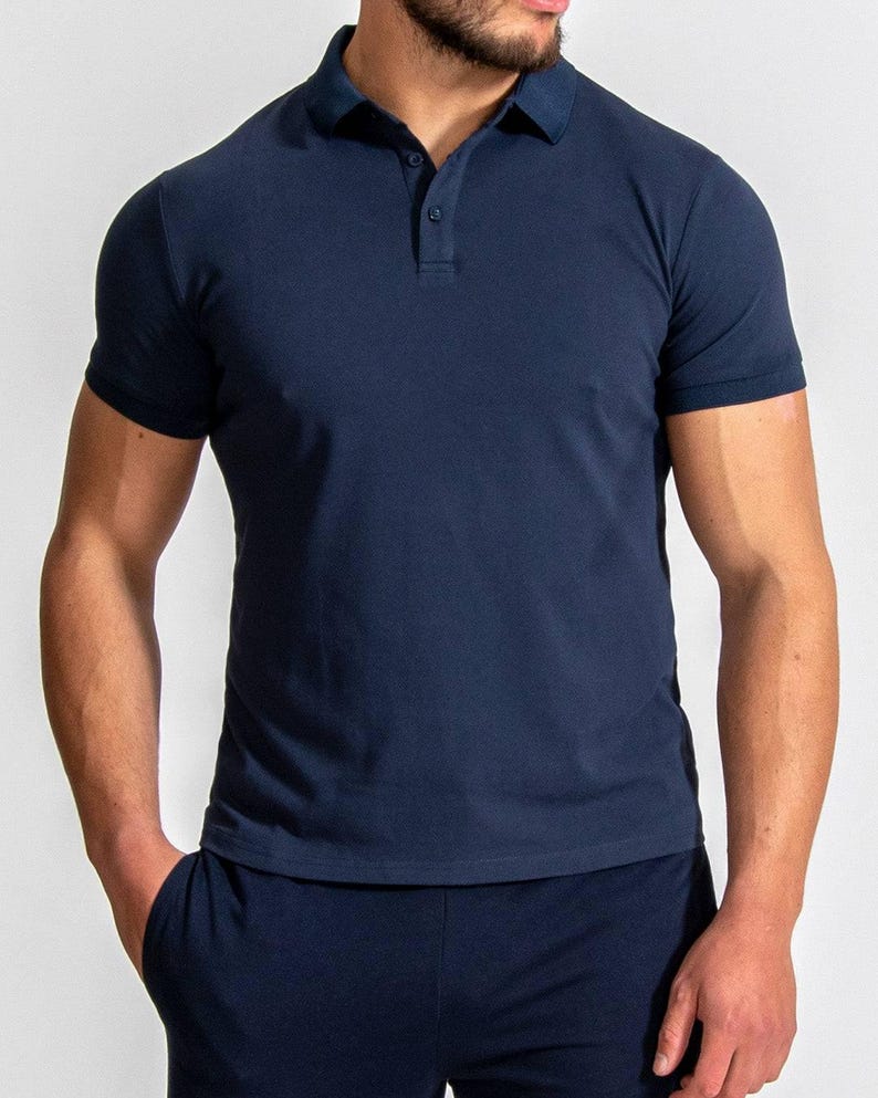 May include: Navy blue polo shirt with short sleeves and a classic collar. The shirt has a three-button placket and is made of a soft, breathable fabric. The shirt is a solid color and is suitable for casual or semi-formal wear.