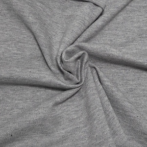 May include: Close-up of gray fabric with a textured surface. The fabric is folded and draped, creating soft shadows and highlights. The material appears to be a medium-weight knit, suitable for apparel or home decor projects.