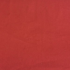 Pu&ograve; includere: Uno sfondo di tessuto rosso solido con una texture liscia.