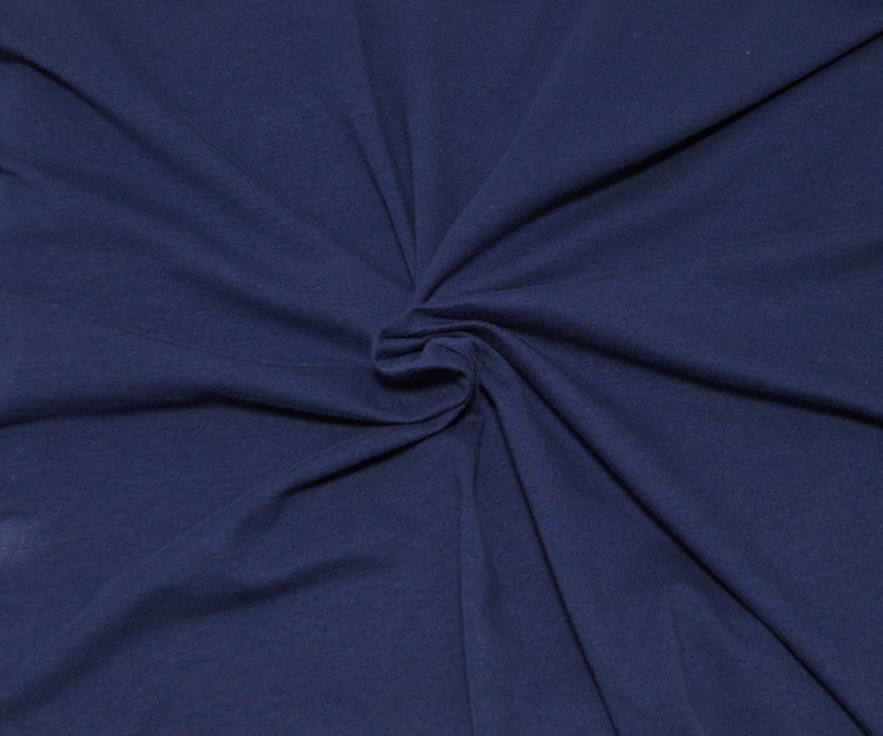 May include: A solid dark navy blue fabric with a smooth, matte texture. The material is gathered in the center, creating soft, radiating folds and natural drapes that extend outward toward the edges of the frame, showcasing the textile's flexibility.