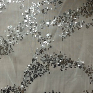 May include: White sheer fabric with silver sequins scattered in a wavy pattern.