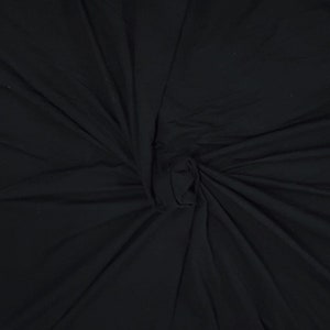 May include: Black fabric with a smooth, soft texture. The fabric is folded and twisted, creating a swirling pattern.