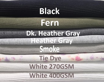 Op de afbeelding: Een stapel gevouwen wafelgebreide stoffen in verschillende kleuren met de labels Black, Fern, Dk. Heather Gray, Heather Gray, Smoke, Tie Dye, White 270GSM en White 400GSM. Het textuurrijke materiaal is horizontaal gestapeld met witte tekst.