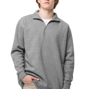 May include: A gray sweatshirt with a quarter-zip collar. The long-sleeved top has a relaxed fit and ribbed cuffs. The model is wearing a white undershirt and khaki pants. The sweatshirt is a versatile piece of casual apparel.
