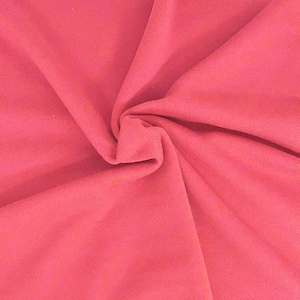 May include: Close-up of a coral-colored fabric with a textured surface. The fabric is gathered and folded, creating a swirling pattern. The color is a vibrant, warm shade of pink.