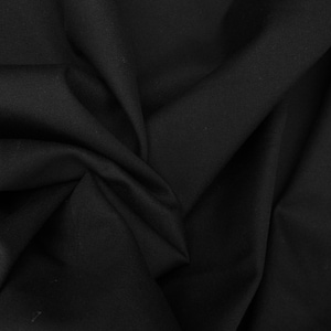 May include: A solid black fabric with a smooth, matte texture, featuring deep folds and soft, flowing drapes that create a series of shadows and highlights across the surface, emphasizing the dense, opaque quality of the material throughout.