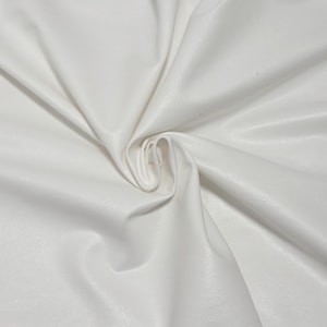 Pode incluir: Close-up de tecido branco com uma superf&iacute;cie lisa e ligeiramente texturizada. O material &eacute; dobrado e drapeado, criando sombras suaves e destaques. O tecido parece ser um material sint&eacute;tico, possivelmente couro sint&eacute;tico ou um t&ecirc;xtil semelhante.