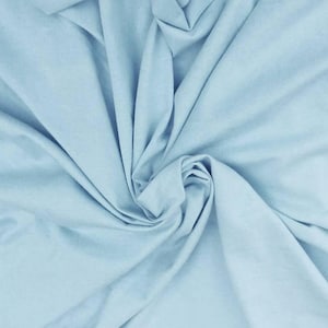 Puede incluir: Una tela de color azul claro s&oacute;lido con una textura suave, dispuesta en una serie de pliegues suaves y en cascada que crean sombras y reflejos naturales en la superficie, enfatizando el color consistente y el acabado mate del material.
