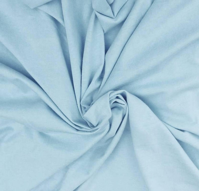 Puede incluir: Una tela de color azul claro s&oacute;lido con una textura suave, dispuesta en una serie de pliegues suaves y en cascada que crean sombras y reflejos naturales en la superficie, enfatizando el color consistente y el acabado mate del material.