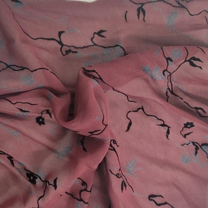 May include: A sheer fabric with a floral pattern in shades of pink and black. The fabric is lightweight and has a delicate feel.