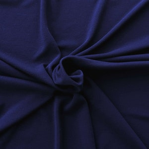 May include: A close-up of a dark navy blue fabric with soft folds and subtle texture. The fabric is draped, creating shadows and highlights that emphasize its smooth surface. The overall appearance suggests a flowing, luxurious material.