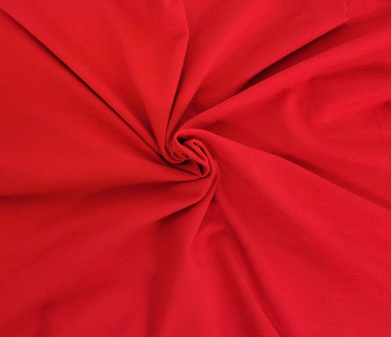 May include: A vibrant red fabric with a smooth, matte texture, displayed with deep, flowing folds that radiate from a central point, creating a series of soft, natural shadows and highlights across the surface of the solid-colored textile material.