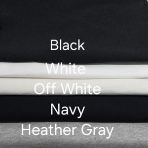 May include: A stack of fabric samples in black, white, off-white, navy, and heather gray. The colors are labeled with white text. The black fabric is at the top, with the other colors layered below.