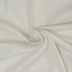 May include: Close-up of a white ribbed fabric with a soft, textured surface. The fabric is folded and draped, creating a smooth, flowing look.