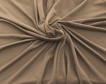 May include: A close-up of a brown fabric with a soft, wrinkled texture. The fabric is folded and draped in a way that creates a swirling pattern.