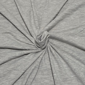 May include: A heather gray fabric with a soft, jersey-like texture. The material is gathered in the center, creating radiating folds and drapes that extend outward toward the edges, showcasing the consistent light gray color and fine knit pattern.