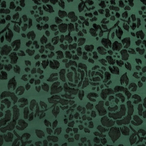 May include: A dark green fabric with a repeating pattern of black floral designs. The fabric has a velvety texture.