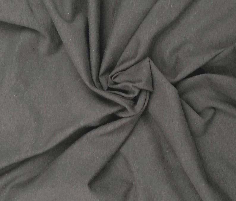 May include: A solid charcoal gray fabric with a soft, matte texture. The material is draped in loose, flowing folds, creating natural shadows and highlights across the surface that emphasize the consistent, deep gray color and fine weave.