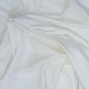 May include: White fabric with soft folds and wrinkles. The fabric is smooth and has a subtle sheen.