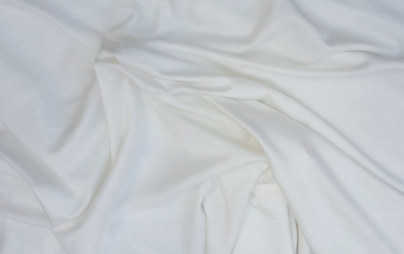 May include: White fabric with soft folds and wrinkles. The fabric is smooth and has a subtle sheen.